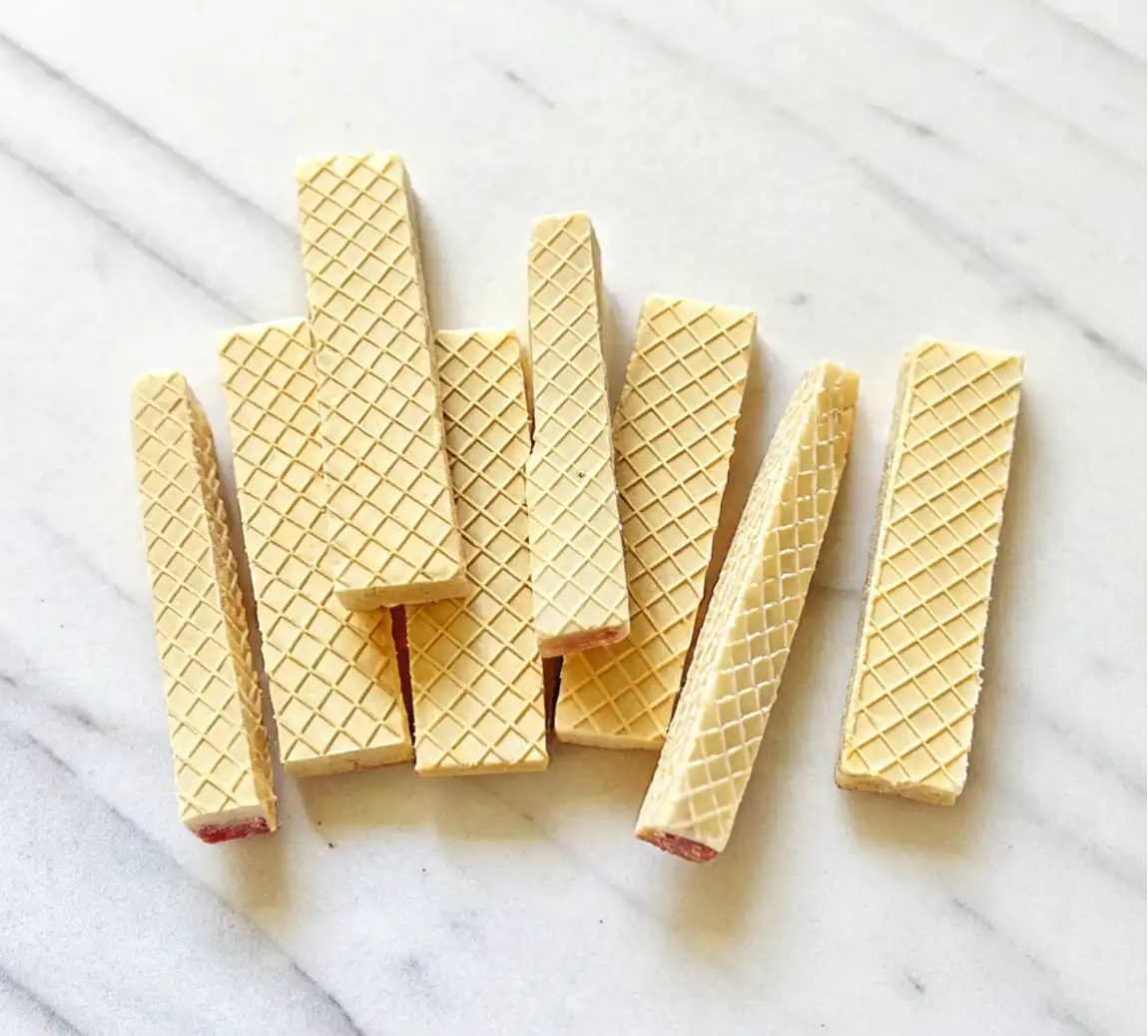 Cutting vanilla wafers into pencil-shaped cookies