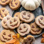 Milk chocolate stuffed jack-o'-lantern cookies stacked on a wooden table.