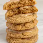 Stack of iced cinnamon brown sugar oatmeal cookies with vanilla glaze dripping down the sides on white plate