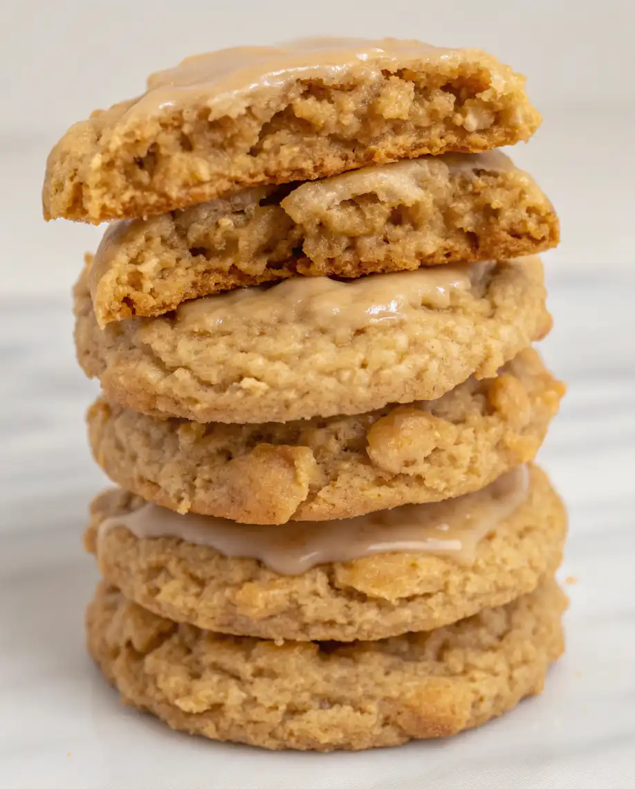 Stack of iced cinnamon brown sugar oatmeal cookies with vanilla glaze dripping down the sides on white plate