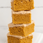 Sliced pumpkin spice cake with cinnamon cream cheese frosting on rustic wooden board