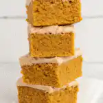 Sliced pumpkin spice cake with cinnamon cream cheese frosting on rustic wooden board